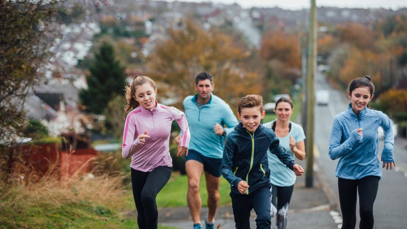 A family of four running together outside