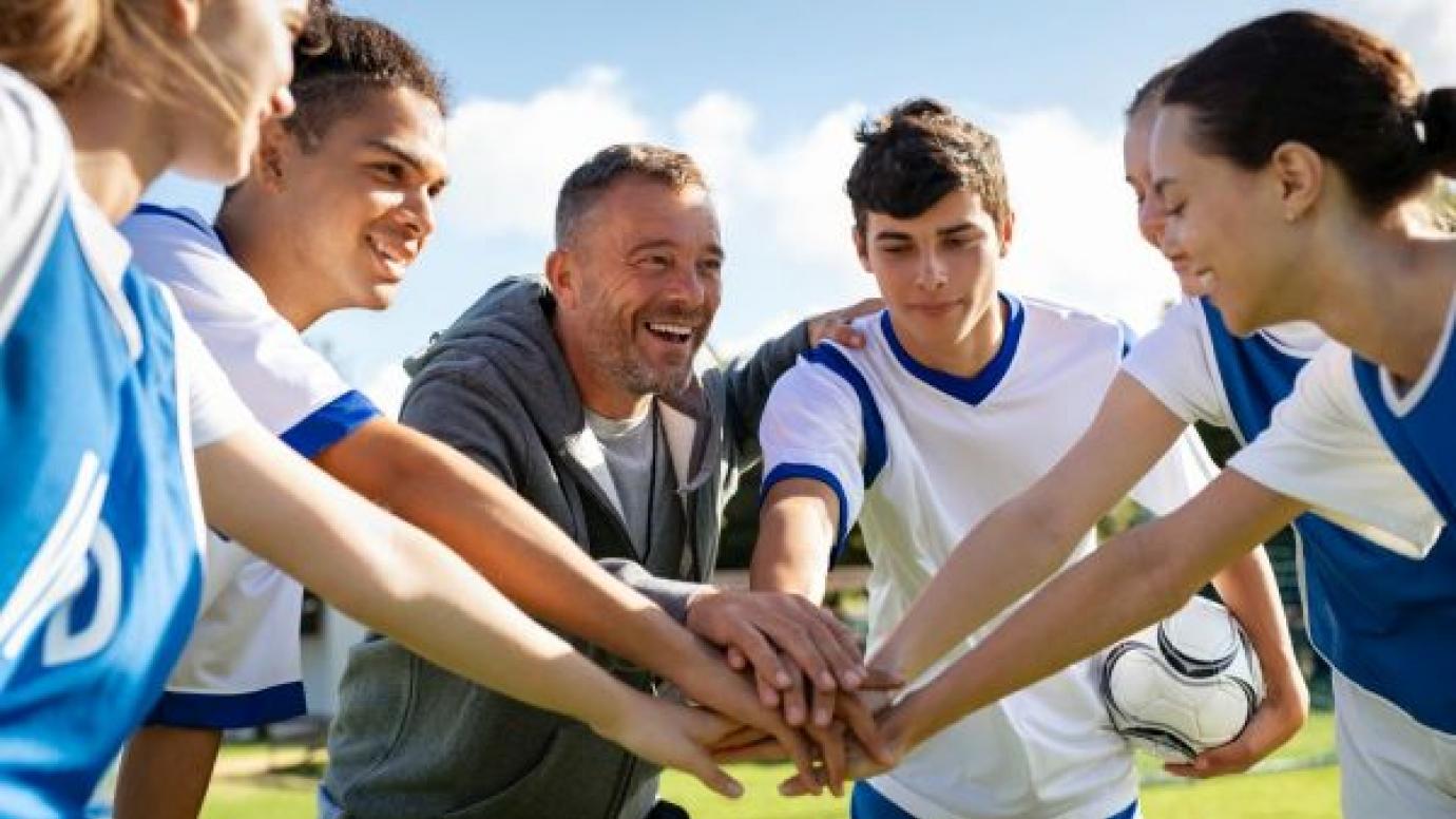 Coach and players huddle on pitch