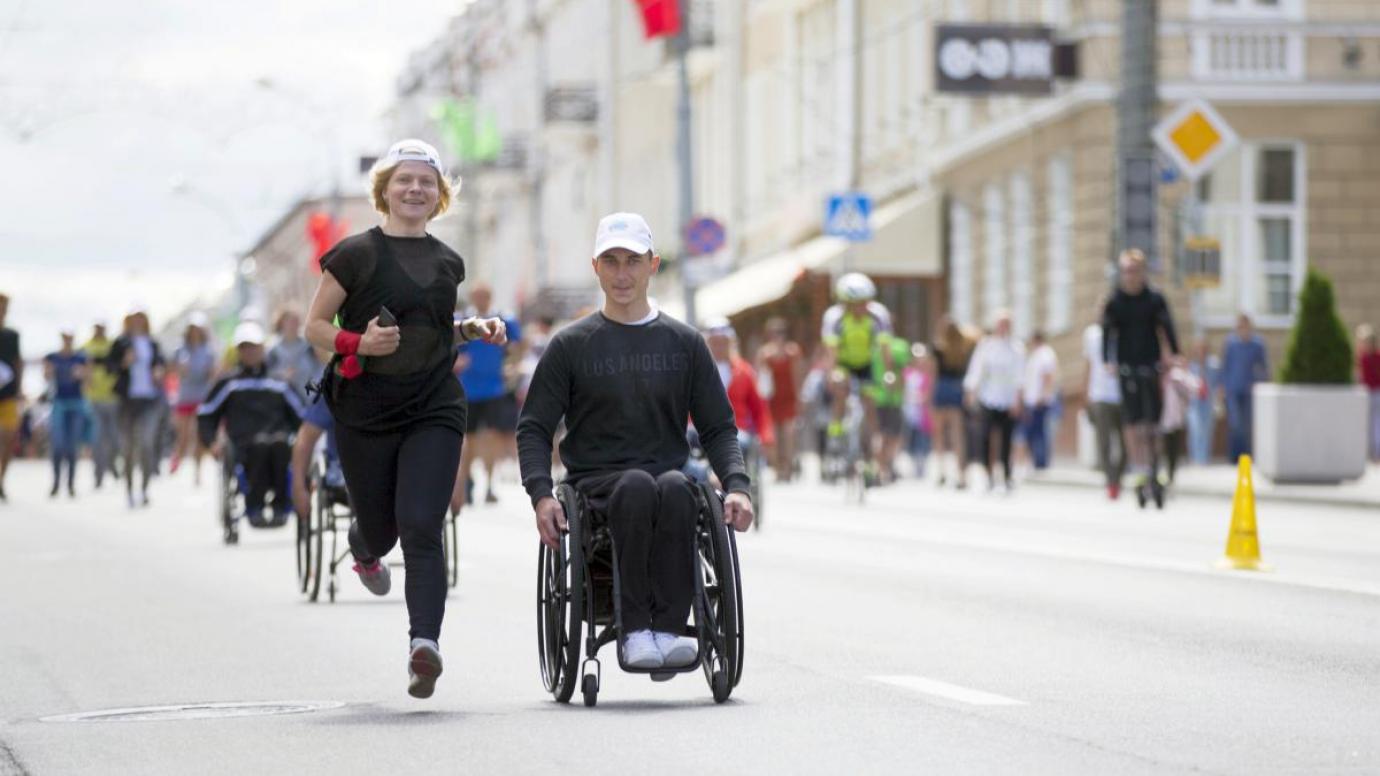 Runner and wheelchair participant side by side in a road race