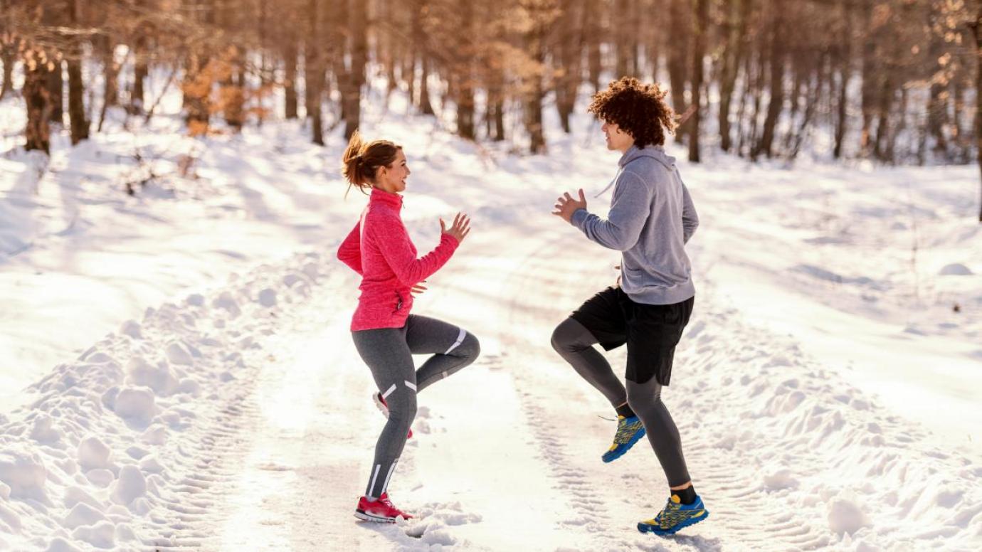 Two athletes warming up in a snow covered landscape