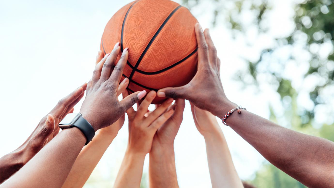 Close-up of multi-ethnic people holding basketball above