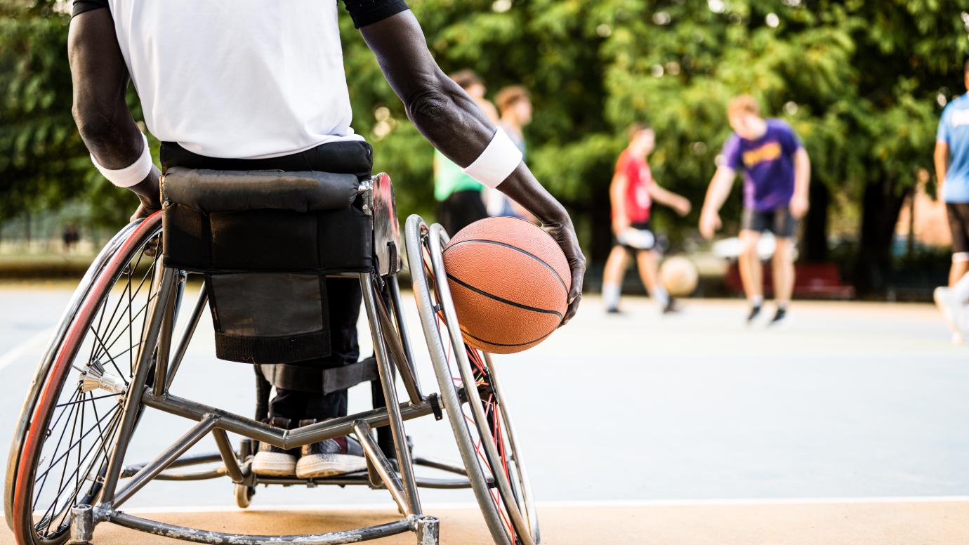 african basketball player in wheelchair waiting to play on open air ground, concept of accessibility to sports for disabled athlete, social inclusion