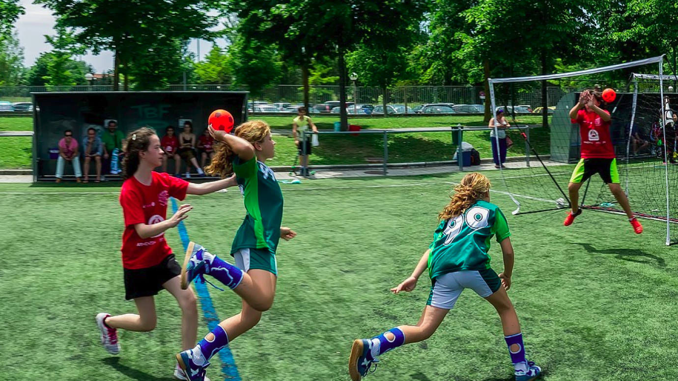 Girls playing handball on an outdoor pitch