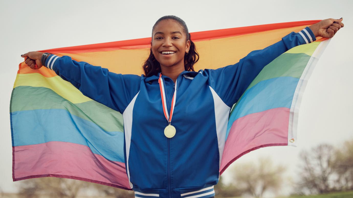 Female athlete holding a pride flag.