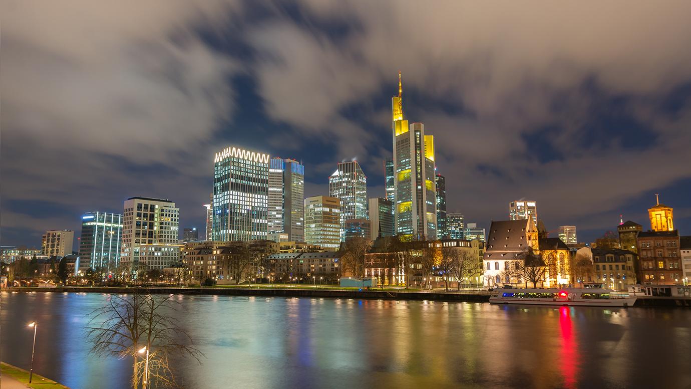 Skyline of the city of Frankfurt (Germany) at night, with the river Main in the foreground