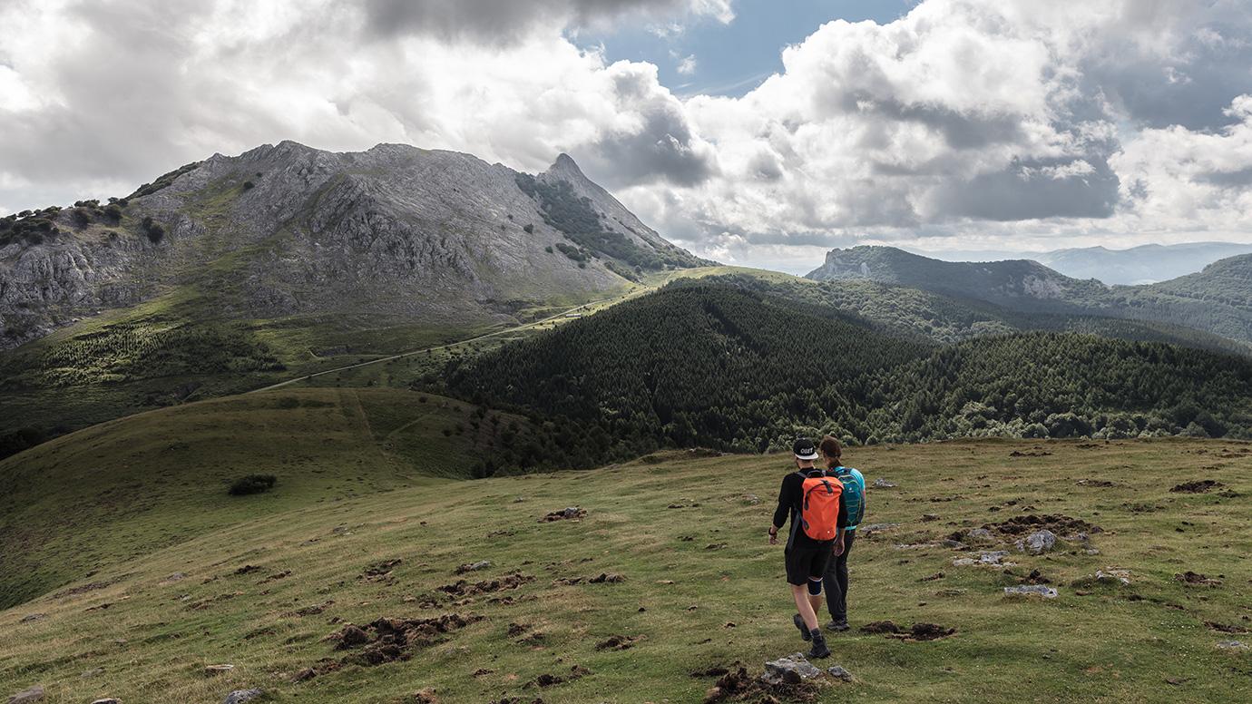 View of two hikers walking on hilly terrain in the Basque countryside
