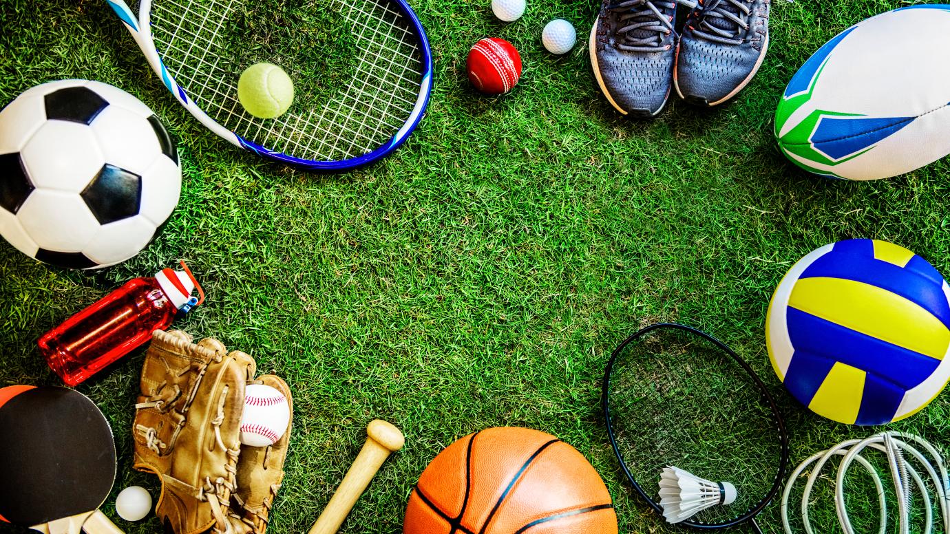 A selection of equipment for various sports on green grass