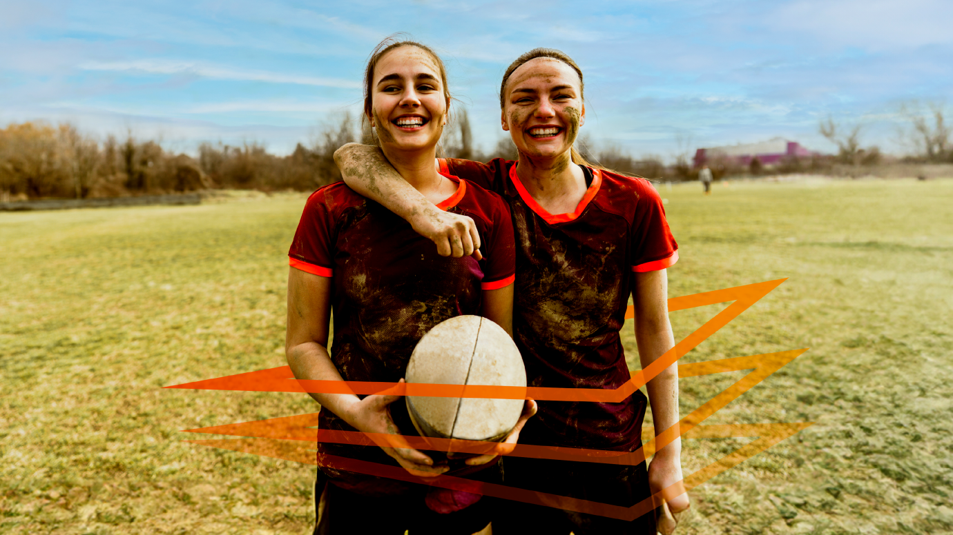 Two female rugby players smiling on a pitch