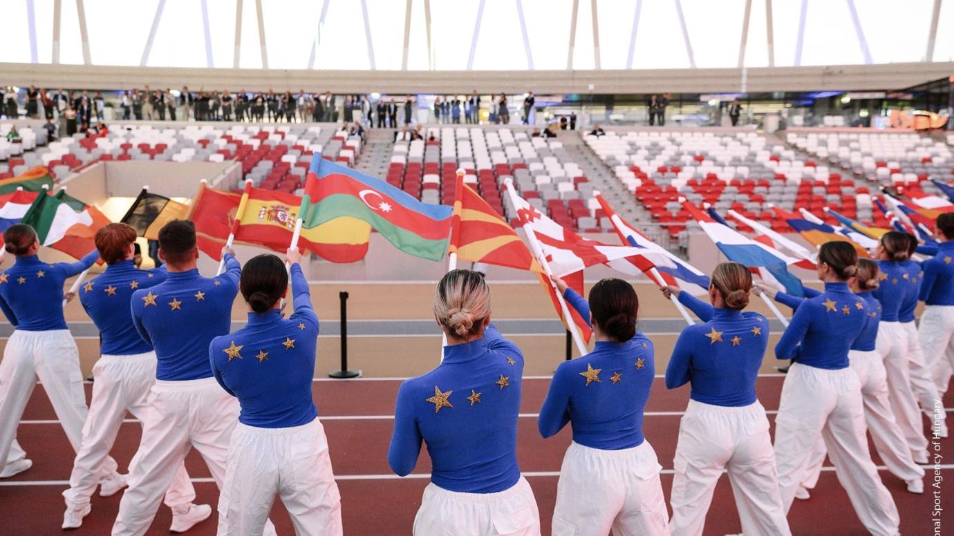 athletes standing in half circle and holding the flags of different countries